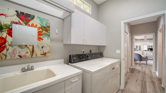 washroom featuring cabinets, separate washer and dryer, light hardwood / wood-style flooring, and sink