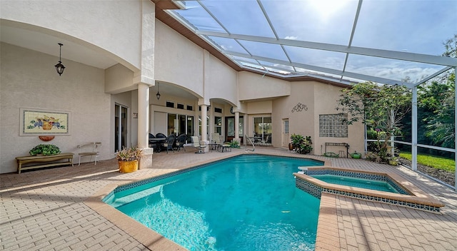 view of swimming pool with glass enclosure, an in ground hot tub, and a patio area