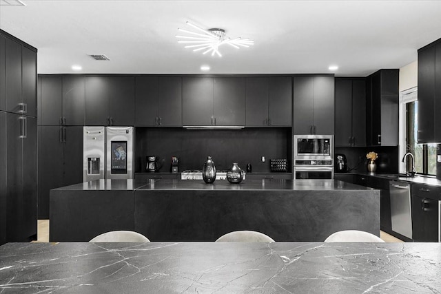 kitchen featuring tasteful backsplash, a spacious island, sink, and stainless steel appliances