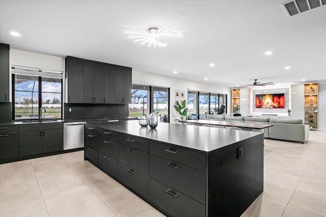 kitchen with a healthy amount of sunlight, ceiling fan, dishwasher, and a spacious island