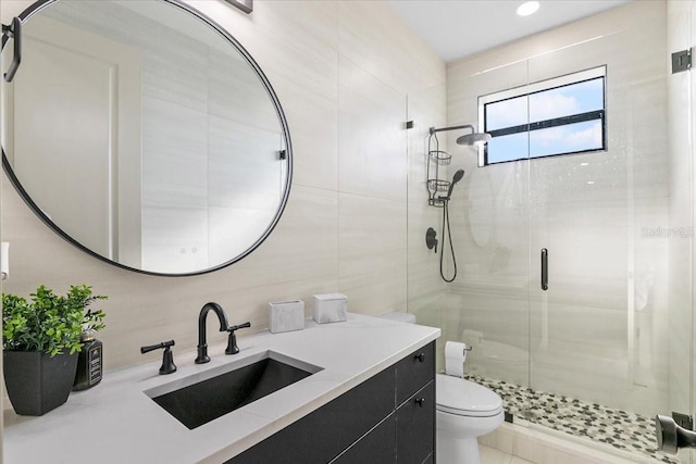 bathroom with tile walls, vanity, an enclosed shower, and toilet