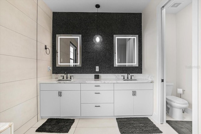 bathroom with vanity, toilet, and tile walls