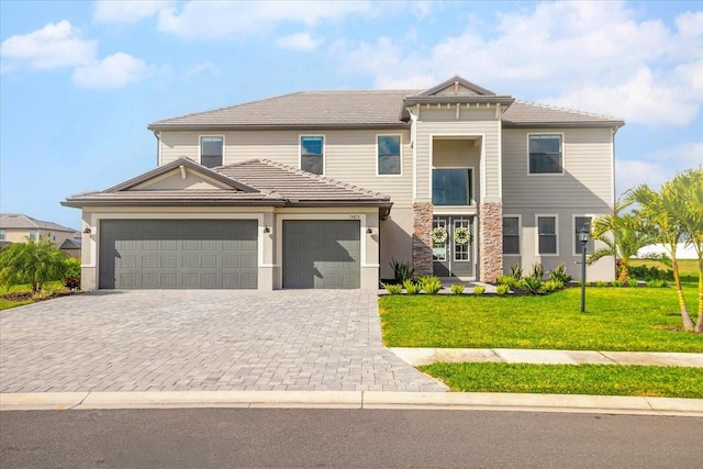 view of front of property with a garage, a tiled roof, decorative driveway, and a front yard