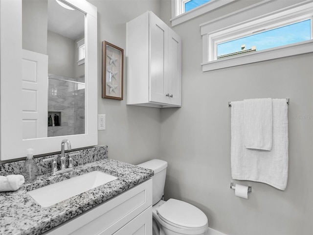 bathroom with vanity, toilet, and a shower with door