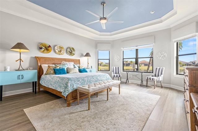 bedroom with a tray ceiling, ceiling fan, ornamental molding, and hardwood / wood-style flooring