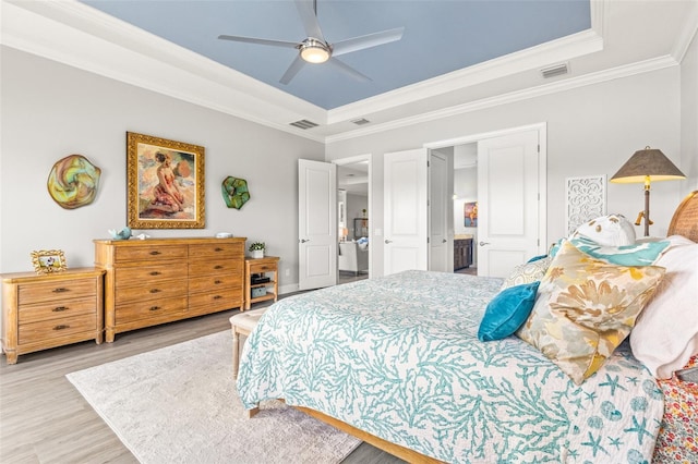 bedroom featuring a raised ceiling, ceiling fan, light hardwood / wood-style floors, and ornamental molding