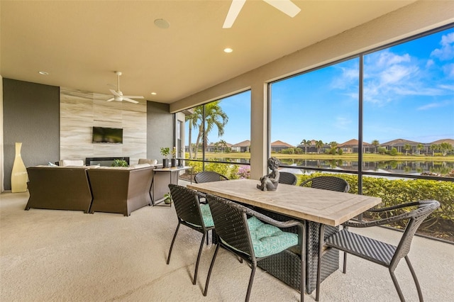 sunroom featuring ceiling fan, a healthy amount of sunlight, and a water view