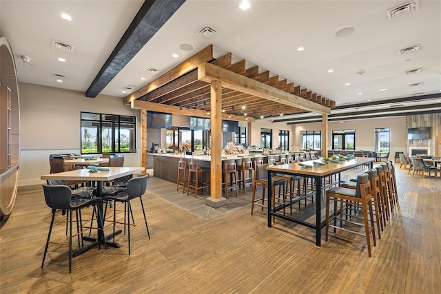 dining space featuring plenty of natural light, beam ceiling, and light hardwood / wood-style flooring