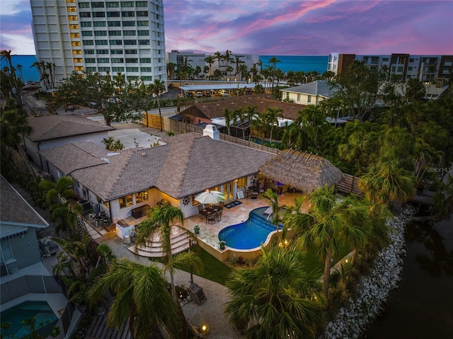 pool at dusk featuring a patio area and a water view