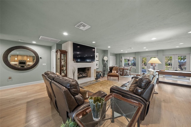 living room featuring light wood-type flooring, french doors, and a large fireplace