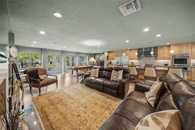 living room with light hardwood / wood-style flooring, a textured ceiling, and billiards