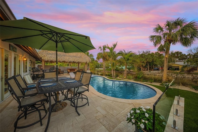 pool at dusk featuring a patio area