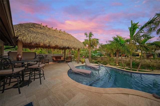 pool at dusk with outdoor lounge area, a mountain view, a gazebo, and a patio