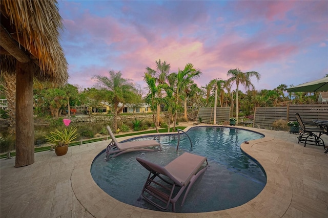 pool at dusk with a patio area