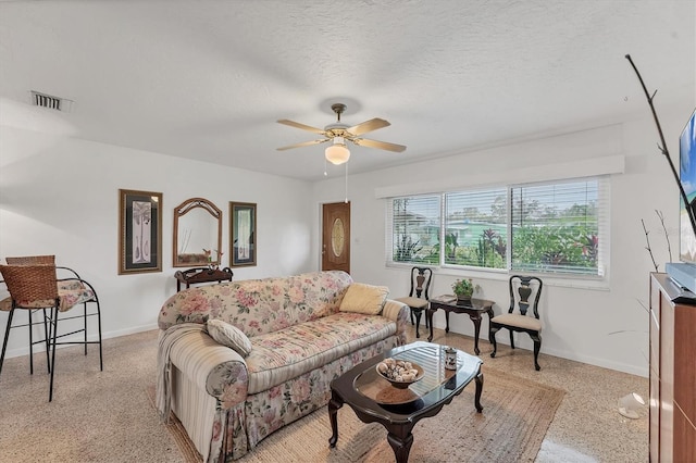 living room with ceiling fan and a textured ceiling