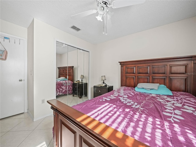 bedroom with ceiling fan, a closet, light tile patterned flooring, and a textured ceiling