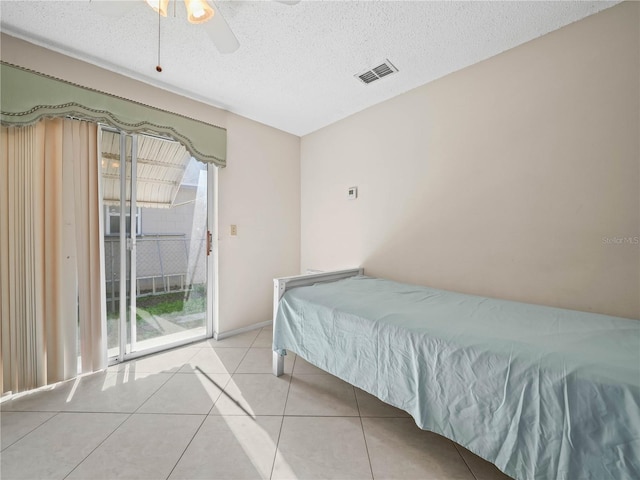 tiled bedroom with ceiling fan, a textured ceiling, and access to outside