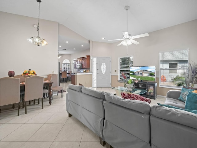 tiled living room with high vaulted ceiling and ceiling fan with notable chandelier