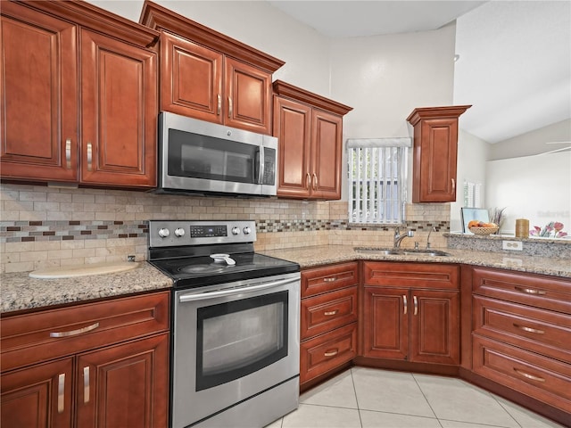 kitchen featuring lofted ceiling, backsplash, sink, light tile patterned floors, and stainless steel appliances