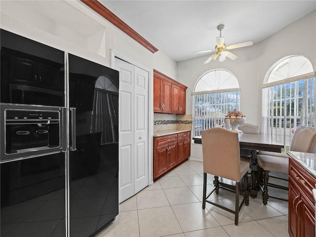 kitchen featuring light stone countertops, backsplash, black refrigerator with ice dispenser, ceiling fan, and light tile patterned flooring