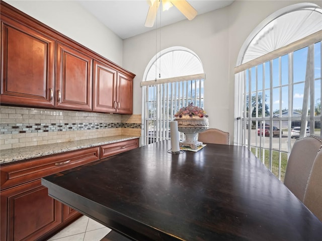 kitchen with plenty of natural light, light stone counters, light tile patterned floors, and backsplash