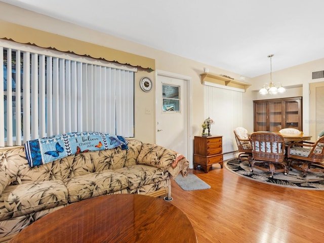 living area featuring visible vents, a chandelier, and wood finished floors