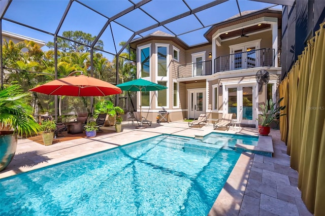 back of house with glass enclosure, french doors, ceiling fan, a balcony, and a patio