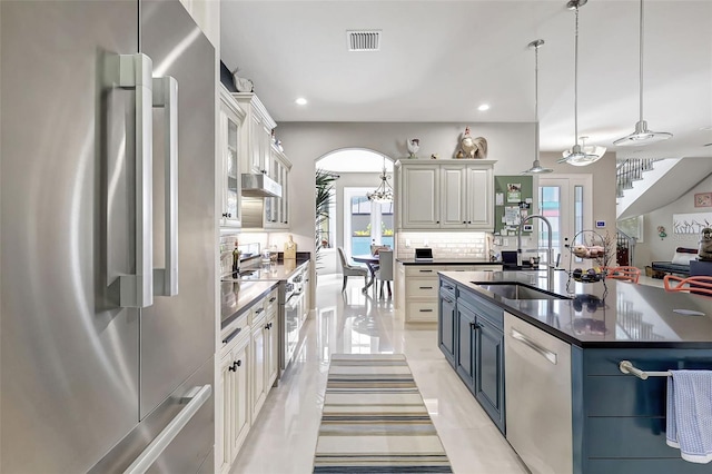 kitchen with pendant lighting, white cabinetry, stainless steel appliances, and a large island with sink