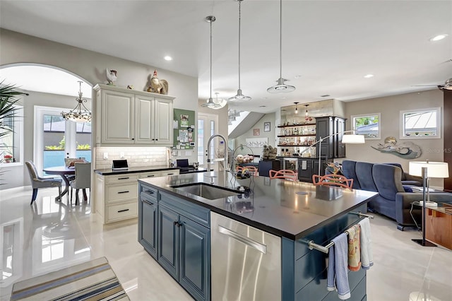 kitchen featuring sink, dishwasher, hanging light fixtures, backsplash, and a kitchen island with sink