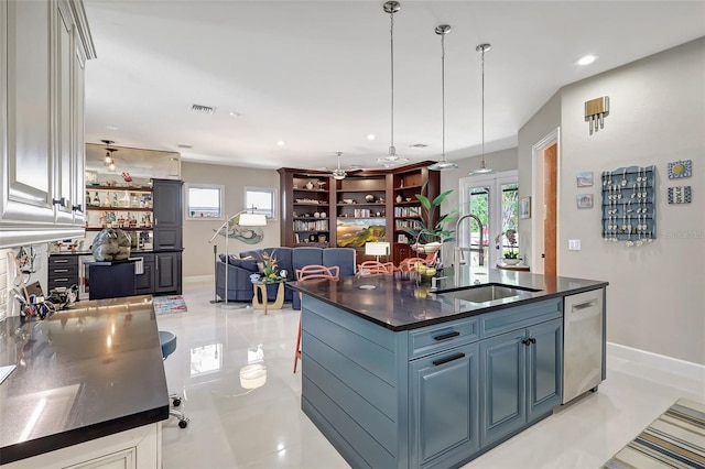 kitchen with sink, hanging light fixtures, stainless steel dishwasher, gray cabinets, and an island with sink