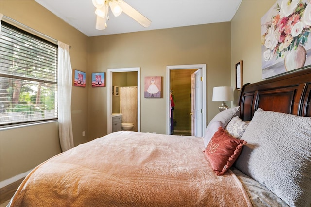 bedroom featuring ensuite bath, ceiling fan, wood-type flooring, and multiple windows