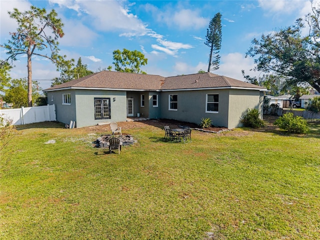 rear view of house with a lawn and an outdoor fire pit