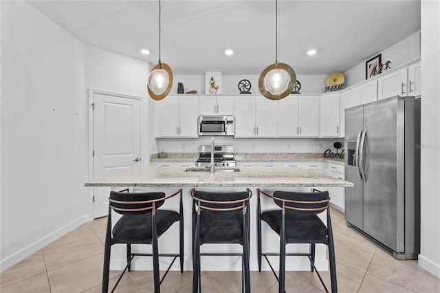 kitchen with stainless steel appliances, white cabinetry, an island with sink, and hanging light fixtures