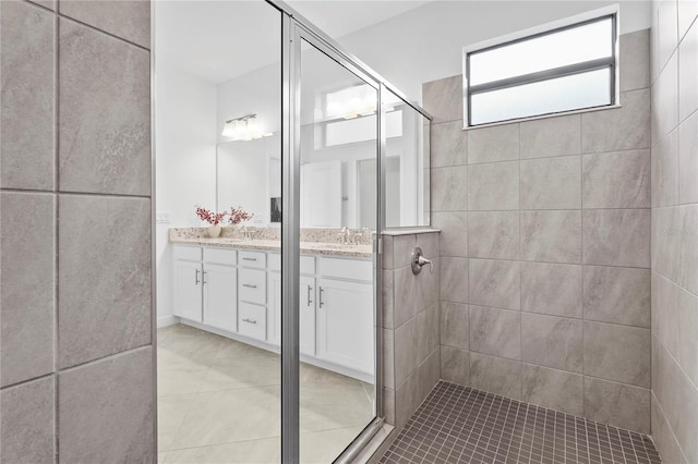 bathroom with tile patterned flooring, a tile shower, and vanity