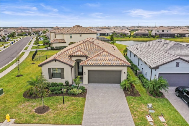 mediterranean / spanish home with a front lawn, a garage, and a water view