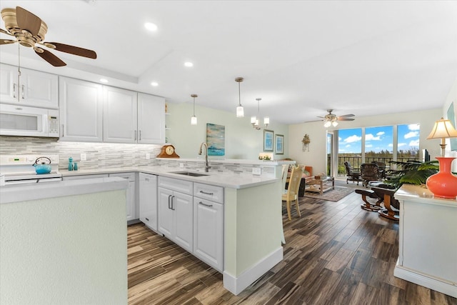 kitchen featuring tasteful backsplash, kitchen peninsula, white cabinets, and white appliances