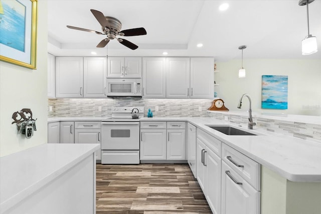 kitchen featuring white appliances, sink, decorative light fixtures, white cabinetry, and kitchen peninsula