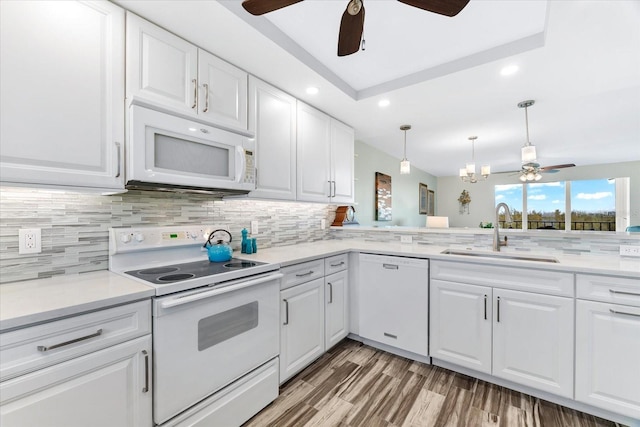 kitchen featuring white cabinets, white appliances, light stone countertops, and sink