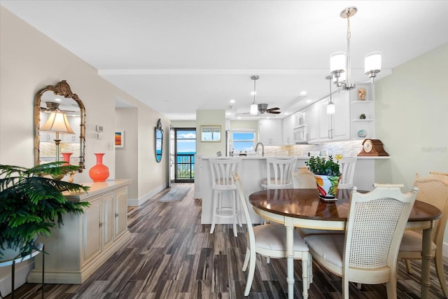 dining space featuring dark wood-type flooring and ceiling fan with notable chandelier