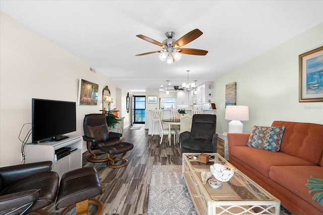 living room featuring ceiling fan with notable chandelier and dark hardwood / wood-style flooring