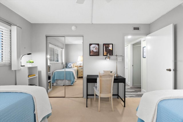 carpeted bedroom featuring multiple windows, a closet, and ceiling fan