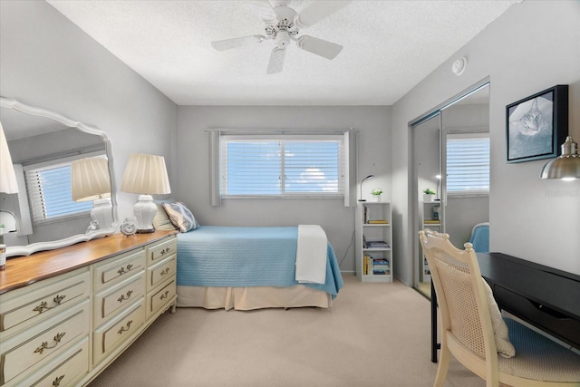 carpeted bedroom featuring multiple windows, ceiling fan, a closet, and a textured ceiling