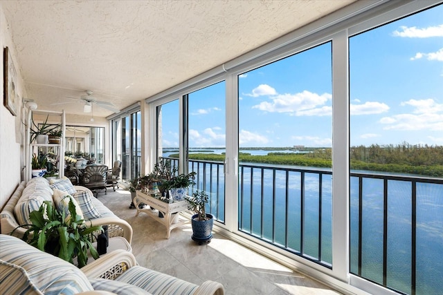 sunroom / solarium with ceiling fan and a water view