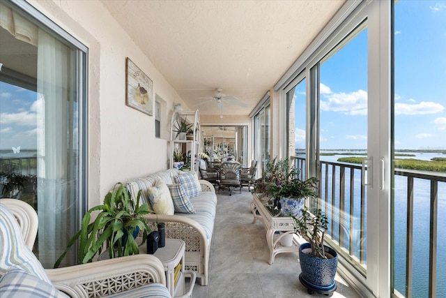 sunroom / solarium featuring ceiling fan and a water view