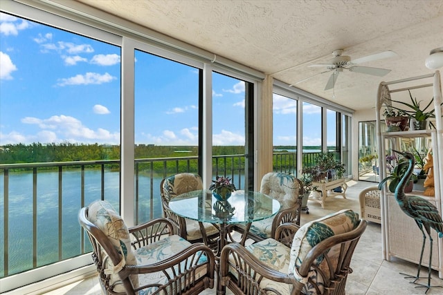 sunroom featuring a water view and ceiling fan