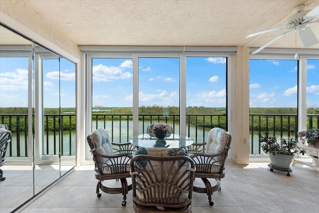 sunroom / solarium featuring ceiling fan, plenty of natural light, and a water view