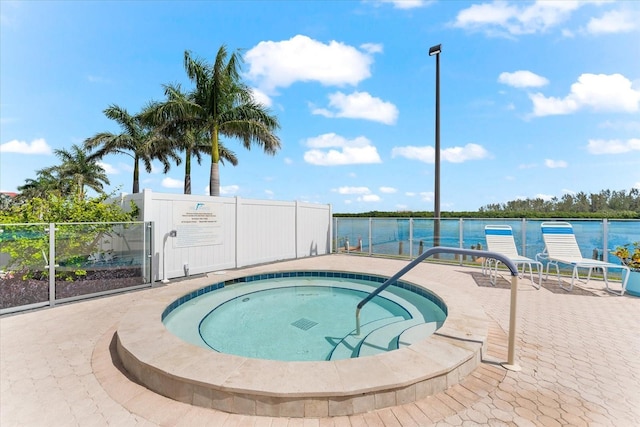 view of swimming pool featuring a water view, a hot tub, and a patio area