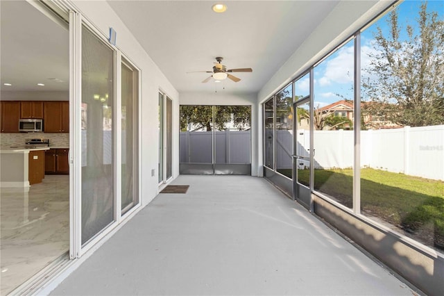 unfurnished sunroom with ceiling fan