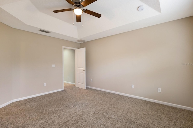 spare room featuring ceiling fan, a raised ceiling, and carpet floors