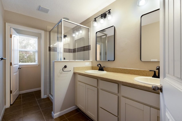 bathroom with vanity, tile patterned floors, a textured ceiling, and a shower with shower door